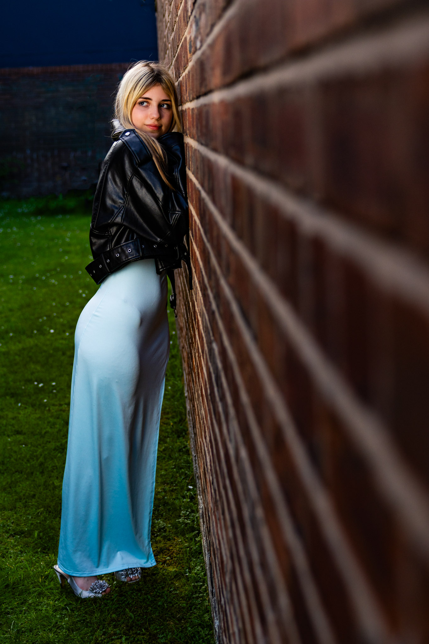 Editorial portrait in a leather jacket against a brick wall