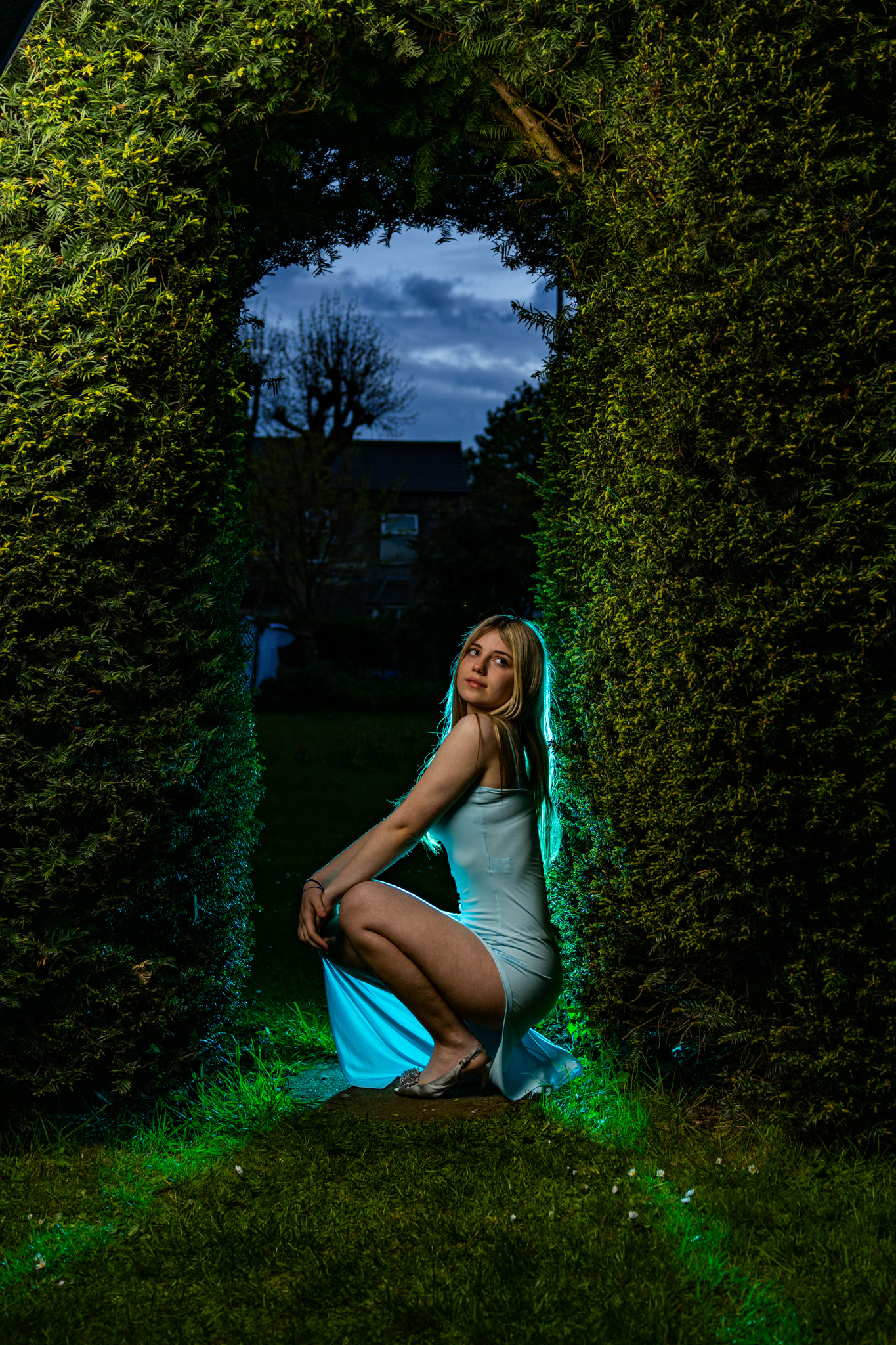 Fashion editorial portrait in a garden hedge arch at dusk